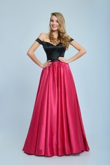 Wonderful girl wearing amazing long pink and black evening dress. Good choice for prom. Girl is very beatiful and has blonde curly hair, nice light make-up. She has pretty smile. Photo was taken on