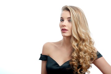 Fototapeta premium Portrait of a beatiful girl with blonde curly hair in a nice evening dress with an open top. Photo was made on the white studio background. She looks gorgeous