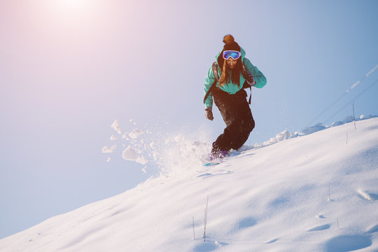 Leisure, sport concept, woman snowboarder riding down the hill