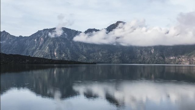 dancing clouds from Rinjani crater lake with reflection indonesia