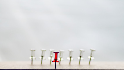 Red pin stands out against white blurred pins in the background	