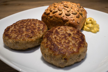 Zwei Frikadellen mit Kürbiskernbrötchen und Senf im Imbiss
