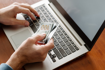 Freelancer working from the comfort of home. Man getting salary on the internet. Male hands holding money