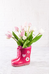 red boots with tulips on wooden background