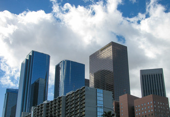 Buildings in the LA skyline on Bunker Hill in downtown Los Angeles viewed from below on Hill Street against a blue sky with white clouds
