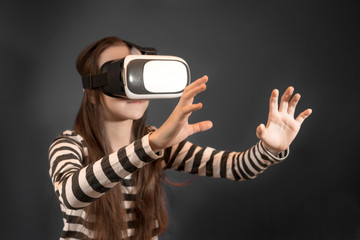 Teenager caucasian girl looking at Virtual Reality Glasses. Virtual reality, vr box. Studio, indoors.