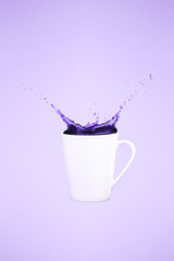 Levitating coffee mug with splashes. Coffee concept. Minimal art trend. Solid pink background