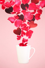 Levitating coffee mug with splashes of rose petals and hearts. Surprise, holiday and coffee love concept. Minimal art trend. Solid background