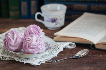 Homemade marshmallow or zephyr with a cup of tea over the wooden background.