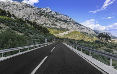 Naklejka premium Country road through the rocky mountains and forest.