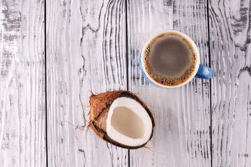 A cup of black coffee and a coconut on a wooden background