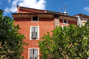 Maison rose ensoleillée avec volets en bois fermés