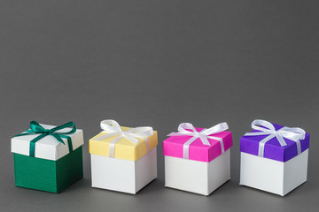 Four gift boxes with ribbons on gray background. Copy space for text.