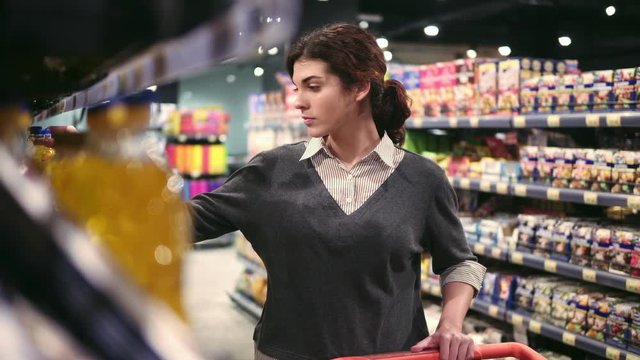 Young beautiful female costumer choosing oil in local grocery store.