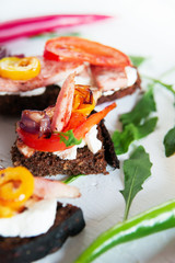 Selection of tasty Bruschetta: tomato and pepper grill, soft cheese, meat, Italian herbs, whole wheat bread.