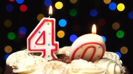 Number 40 on top of cake - forty birthday candle burning - blow out at the end. Color blurred background