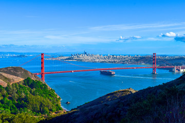 Großes Transportschiff fährt unter der Golden Gate Bridge hindurch, San Francisco Skyline im...