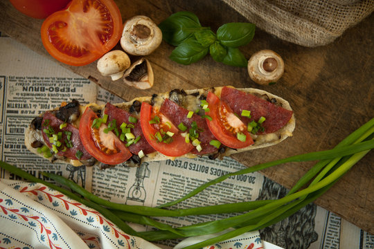 Zapiekanki w starym stylu, Bułka paryska z salami i pomidorem posypana szczypiorkiem. w stylu rustykalnym