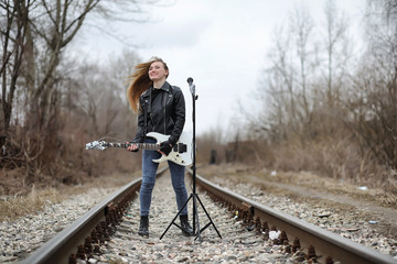  A rock musician girl in a leather jacket with a guitar 