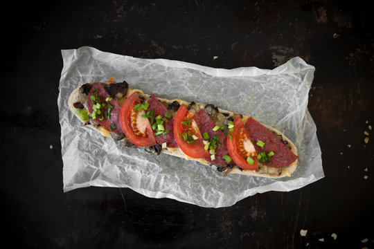 Zapiekanki w starym stylu, Bułka paryska z salami i pomidorem posypana szczypiorkiem. w stylu rustykalnym
