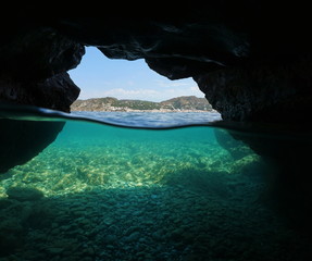 Over and under the sea inside a cavern on the seashore with the Mediterranean village El Port de la Selva and pebbles underwater, Spain, Costa Brava, Girona, Catalonia