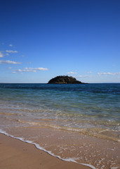 Island with beach with turquoise sea water with rocks