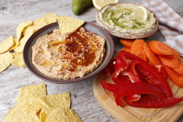 Hummus with sun-dried tomatoes and paprika. Hummus with avocado. Sliced fresh vegetables.