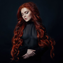 Portrait of redhead sexy woman with long hair on black background. Perfect girl with the blue eyes,...