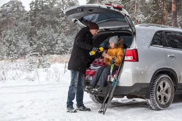 Printed kitchen splashbacks Winter sports Father pouring hot drink for child after sports activities such as ski. Sitting back trunk of suv at winter season. Copyspace