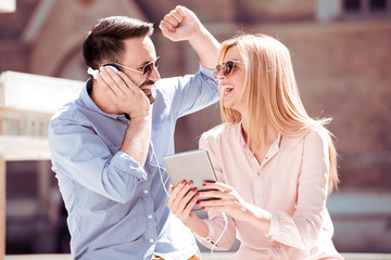 Couple listening music together while sitting in a city.