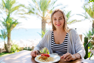 woman eats pasta on the background of the sea