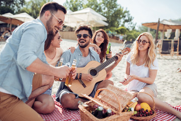 Happy young people having a picnic on the beach.