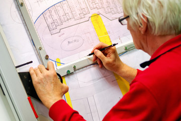 Senior architect working on technical drawing board with ruler and pencil designing building plan
