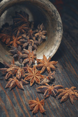 star anise, poured from a bronze mortar on a wooden table close-up
