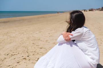 Fototapeta na wymiar Young woman looking away while sitting at sea shore