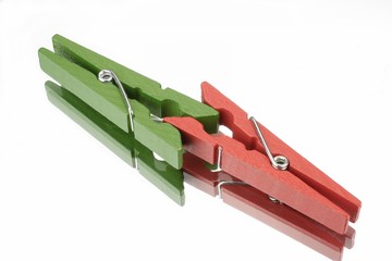 Red and green clothespin in front of white background with mirror reflection