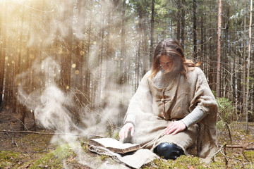 A man in a cassock spends a ritual in a dark forest