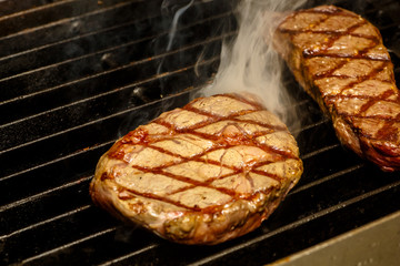 The chef cooks steaks on the grill.