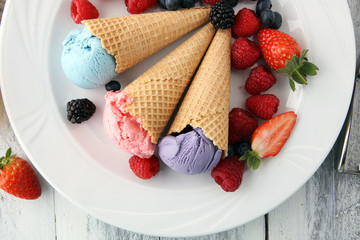 Set of ice cream scoops of different colors and flavours with blueberries, raspberries and blackberries.