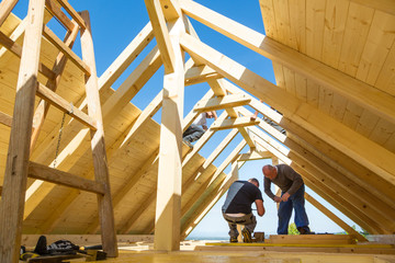 Roof builders mounting prefabricated wooden roof construction. Construction industry concept.
