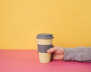 Hand holding take away coffee cup.
