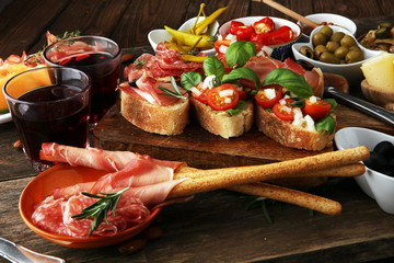 Italian antipasti wine snacks set. Cheese variety, Mediterranean olives, pickles, Prosciutto di Parma, tomatoes, artichokes and wine in glasses