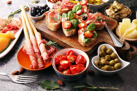 Italian antipasti wine snacks set. Cheese variety, Mediterranean olives, pickles, Prosciutto di Parma, tomatoes, artichokes and wine in glasses