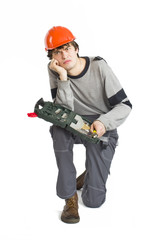 A young man in working grey clothes and orange hard helmet sitting with toolkit on isolated white background.