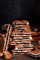 Milk chocolate with vanilla cream and chocolate cookies on a dark background.
