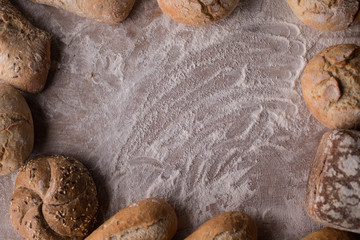 Tradycyjny chleb i bułki na zakwasie z szorstką skórką na rustykalnym drewnianym stole. 