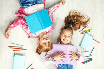 Two funny little girls with books. Flat lay. The concept of childhood, learning, friendship, family, school, lifestyle.
