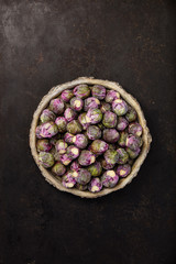 Purple Brussels sprouts in a bowl on dark background