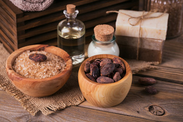Natural cosmetic oil, sea salt and natural handmade soap with cocoa beans on rustic wooden background