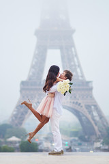 Obraz premium Couple in love with bunch of white roses near Eiffel tower in Paris